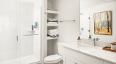 a spacious bathroom with a walk-in shower and shelving