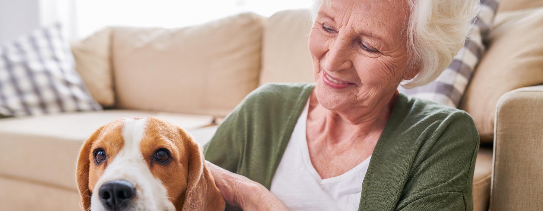 A resident sitting with a dog at Aspendale Northglenn 55 plus apartments in Northglenn, CO, featuring a beige couch.