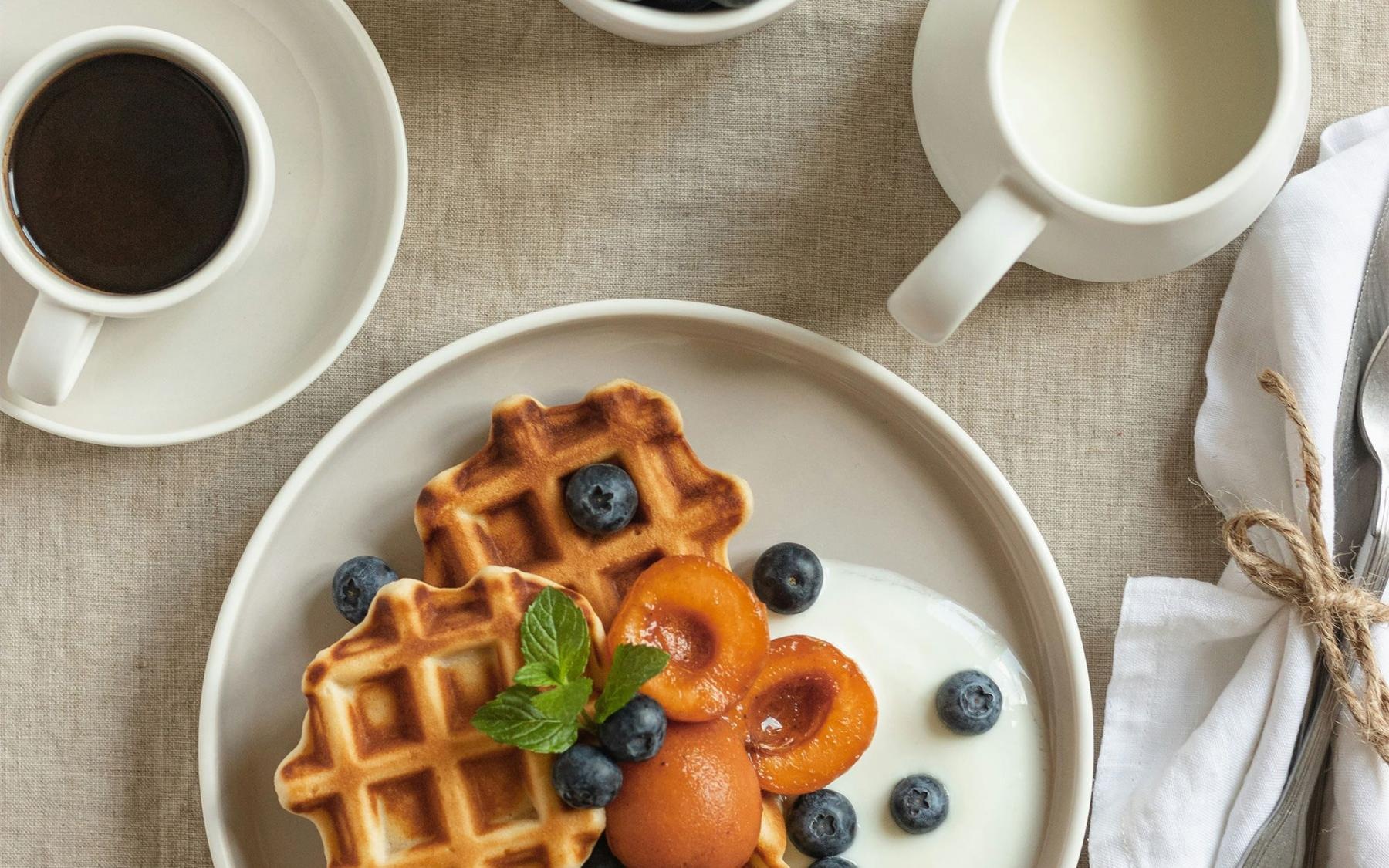 Close to the center of everything a plate of blueberries and waffles and a cup of coffee